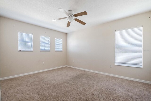 spare room with baseboards, carpet floors, a textured ceiling, and a ceiling fan