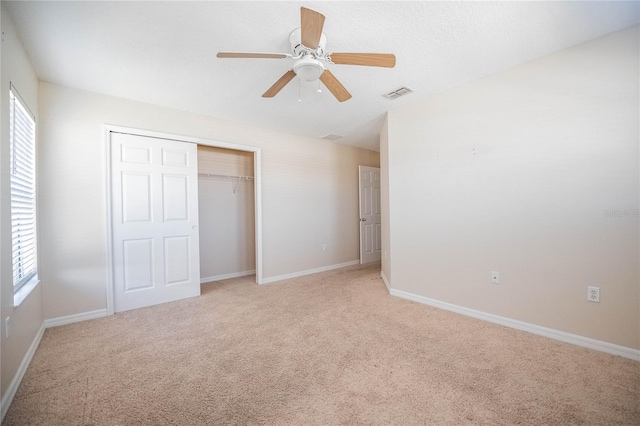 unfurnished bedroom featuring a textured ceiling, light colored carpet, a closet, and ceiling fan