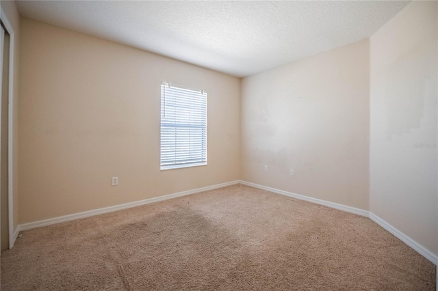 spare room featuring a textured ceiling, baseboards, and carpet floors