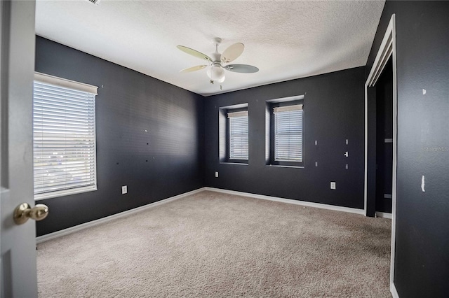 carpeted empty room featuring ceiling fan and a textured ceiling