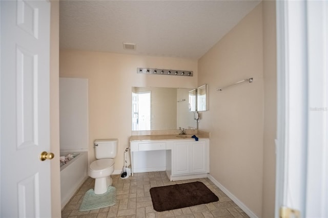 bathroom with vanity, toilet, baseboards, and a textured ceiling