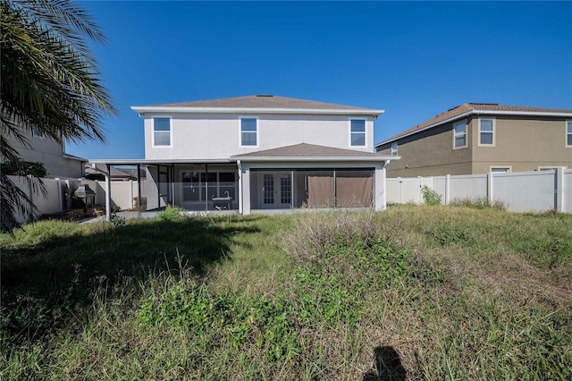 back of house with stucco siding, a fenced backyard, and a sunroom