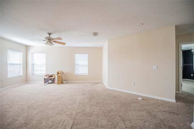 spare room with visible vents, a textured ceiling, carpet, baseboards, and ceiling fan