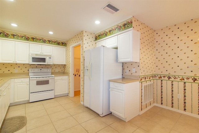 kitchen with white cabinetry, white appliances, and light tile patterned flooring