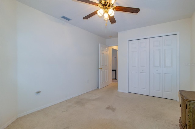 unfurnished bedroom with ceiling fan, light colored carpet, and a closet