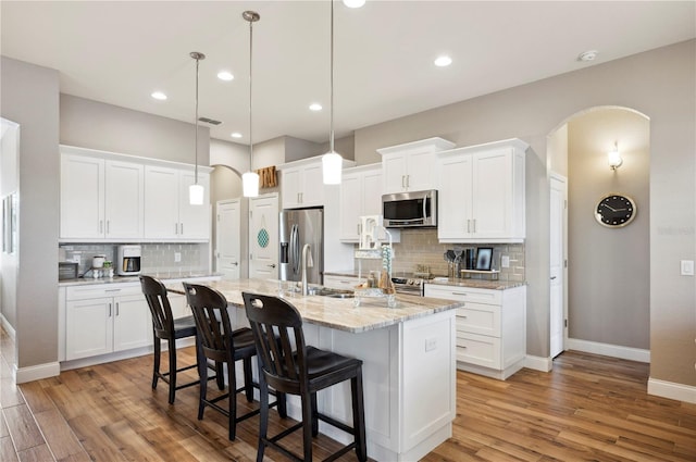 kitchen featuring white cabinetry, appliances with stainless steel finishes, a kitchen island with sink, and pendant lighting