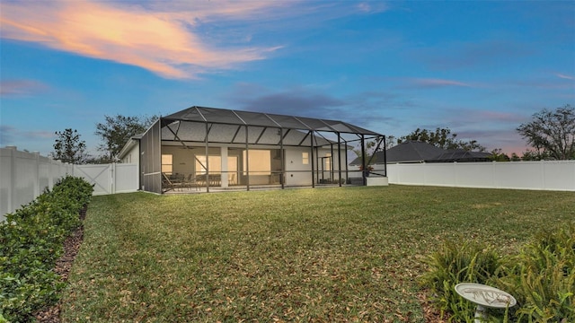 back house at dusk with a yard and glass enclosure