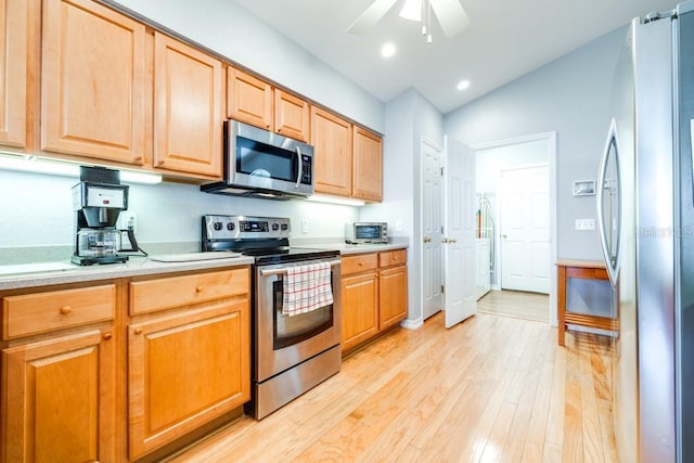 kitchen featuring stainless steel appliances, vaulted ceiling, ceiling fan, and light hardwood / wood-style floors