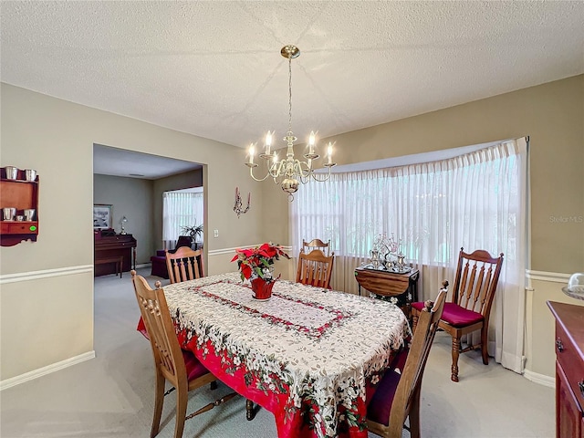 dining room with light colored carpet, a textured ceiling, and an inviting chandelier