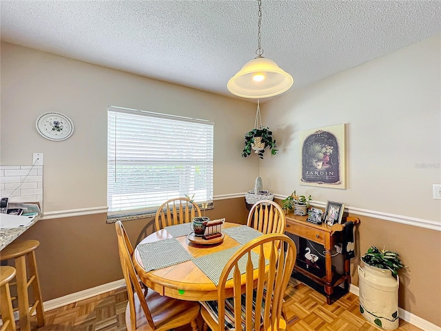 dining space with parquet floors and a textured ceiling