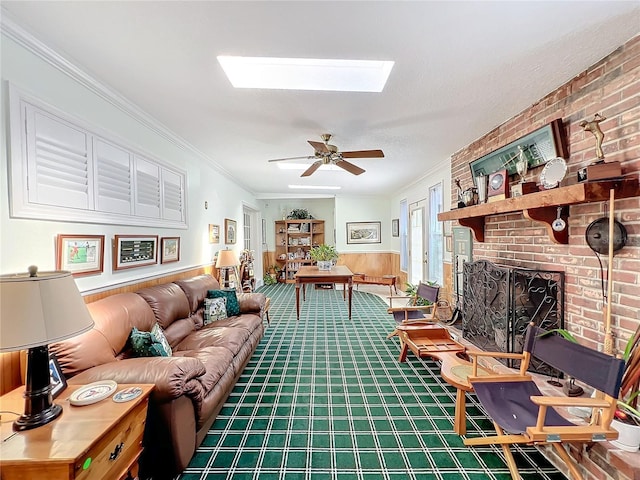 living room with crown molding, ceiling fan, a skylight, carpet floors, and a fireplace