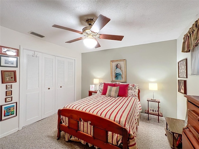 carpeted bedroom with ceiling fan, a closet, and a textured ceiling