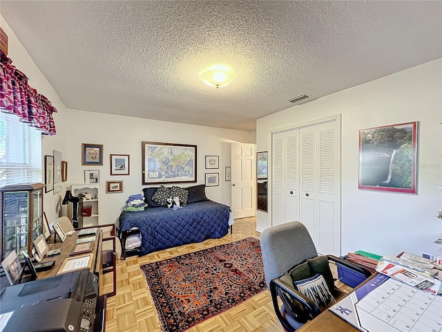 bedroom featuring light parquet floors, a textured ceiling, and a closet