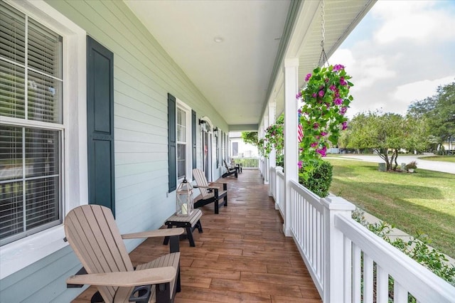 wooden deck featuring covered porch and a lawn