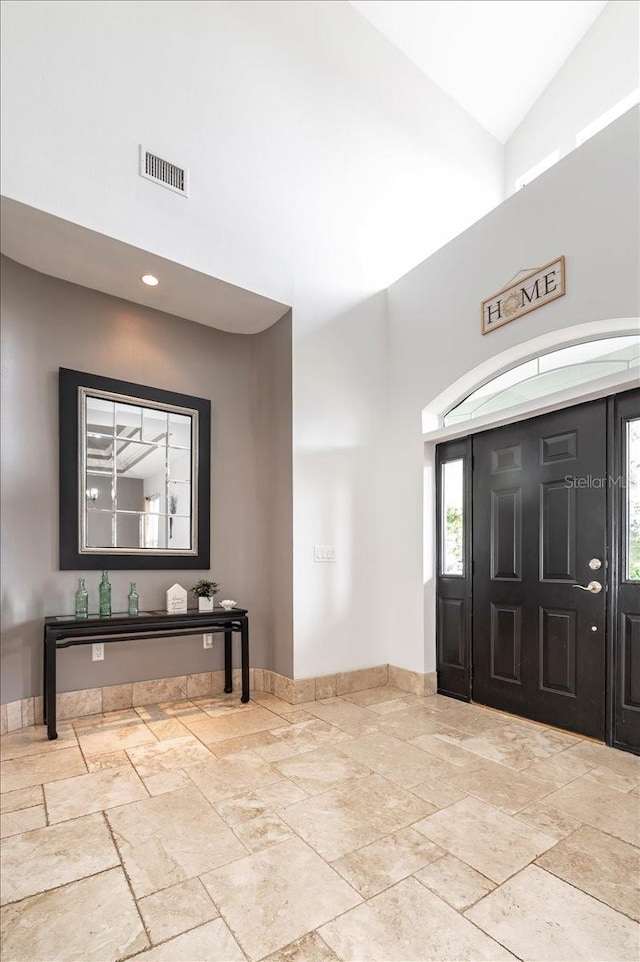 entryway featuring visible vents, a towering ceiling, and baseboards