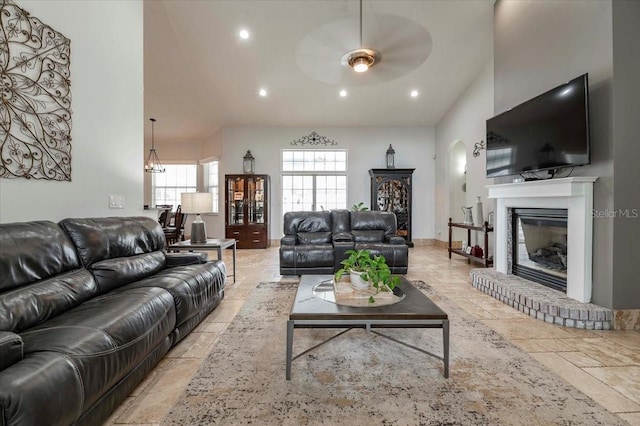 living room with high vaulted ceiling, recessed lighting, a fireplace, a ceiling fan, and stone tile flooring