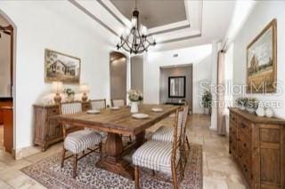 dining space featuring a tray ceiling, a notable chandelier, and arched walkways