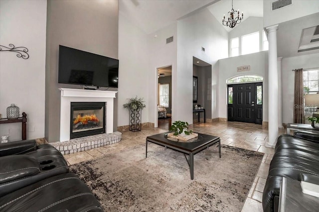 living area featuring stone tile floors, decorative columns, visible vents, and a fireplace