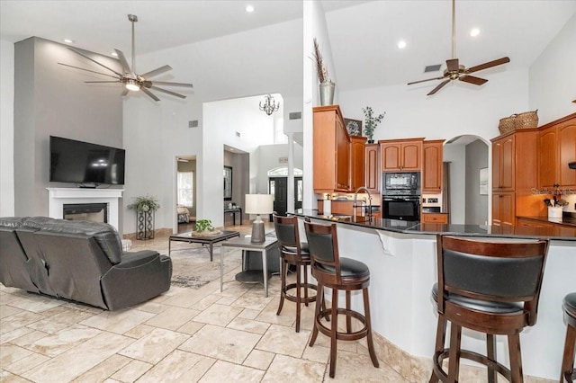 kitchen with arched walkways, open floor plan, ceiling fan, black appliances, and a kitchen breakfast bar