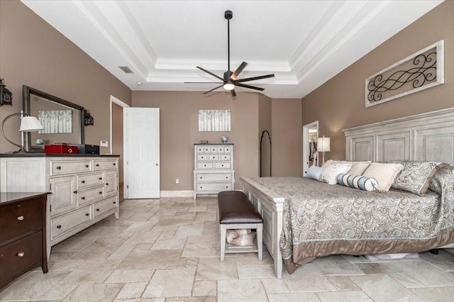 bedroom with stone tile floors, visible vents, baseboards, ornamental molding, and a tray ceiling