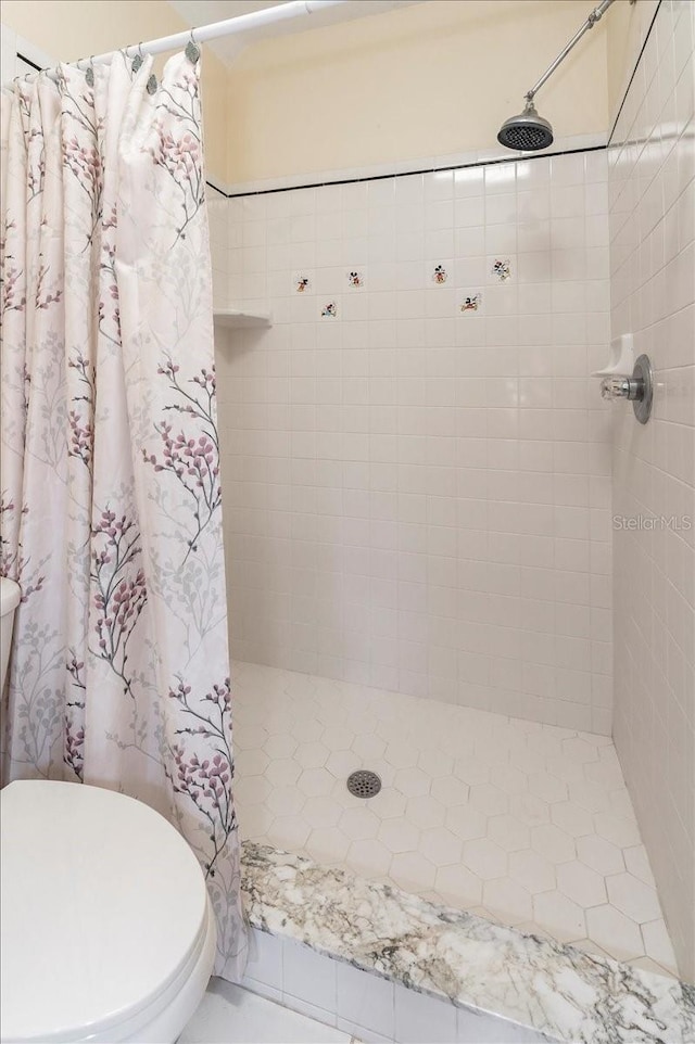 bathroom with a tile shower and toilet