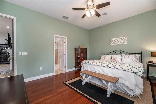 bedroom with connected bathroom, wood finished floors, a ceiling fan, visible vents, and baseboards