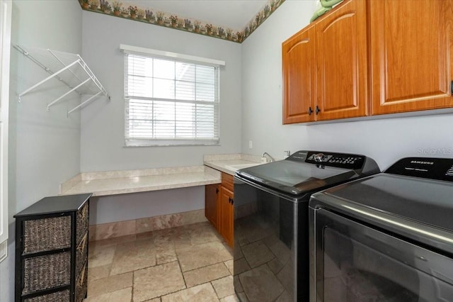 laundry area featuring a sink, stone finish floor, washing machine and clothes dryer, and cabinet space