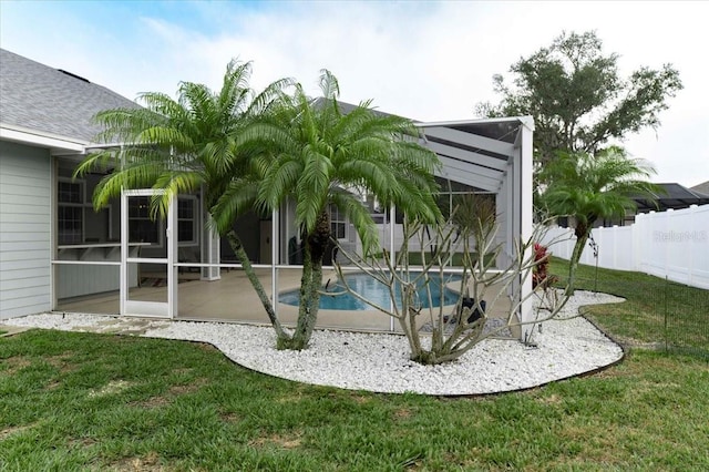 view of pool featuring a patio, glass enclosure, fence, a yard, and a fenced in pool