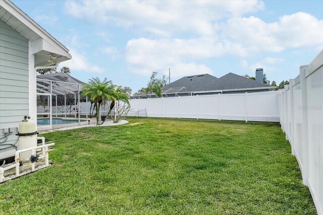 view of yard with glass enclosure, a fenced backyard, and a fenced in pool