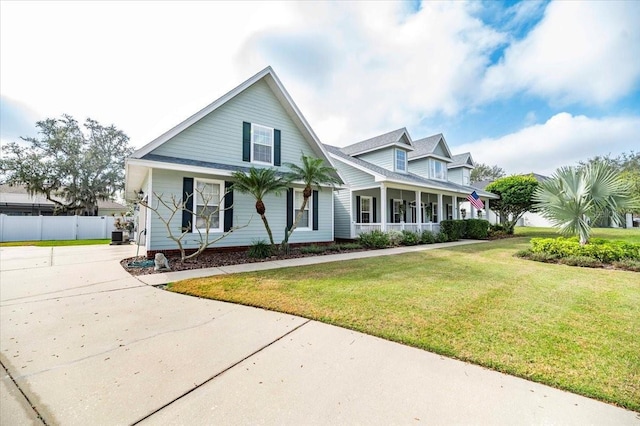 cape cod home with covered porch, fence, driveway, and a front lawn