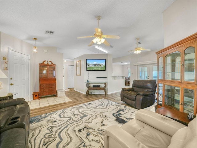 living room with ceiling fan, light hardwood / wood-style floors, and a textured ceiling