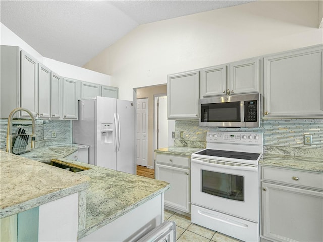 kitchen featuring lofted ceiling, light tile patterned floors, white appliances, sink, and tasteful backsplash