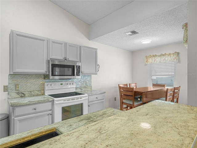 kitchen featuring white electric stove, decorative backsplash, and a textured ceiling