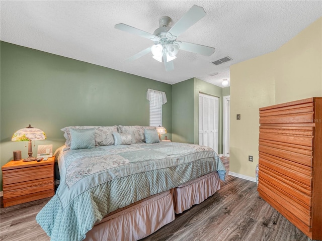 bedroom with hardwood / wood-style flooring, ceiling fan, a closet, and a textured ceiling