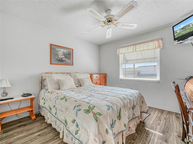 bedroom with hardwood / wood-style flooring, ceiling fan, and a textured ceiling