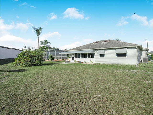 rear view of house with central AC unit and a lawn