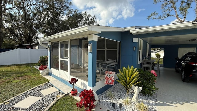 view of home's exterior featuring a yard, a sunroom, and a carport