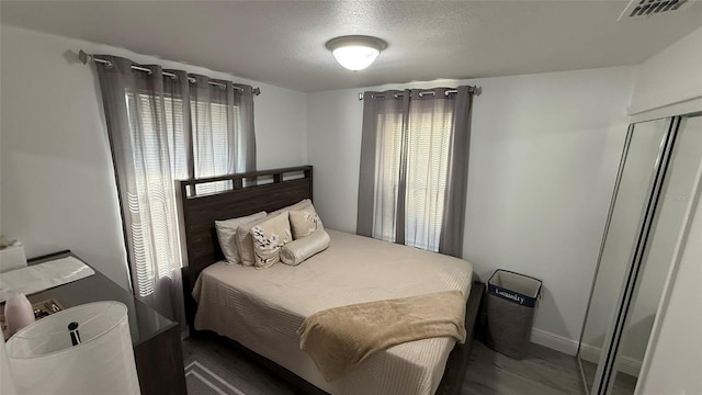 bedroom with dark hardwood / wood-style flooring, a closet, and a textured ceiling