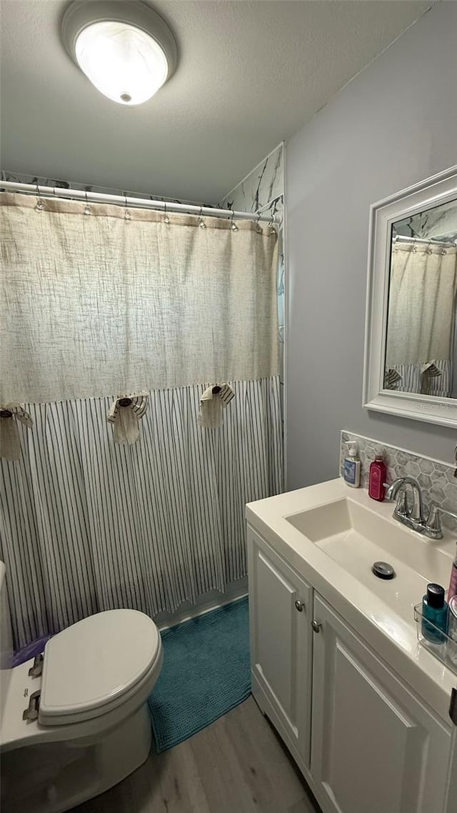 bathroom with walk in shower, toilet, wood-type flooring, a textured ceiling, and vanity