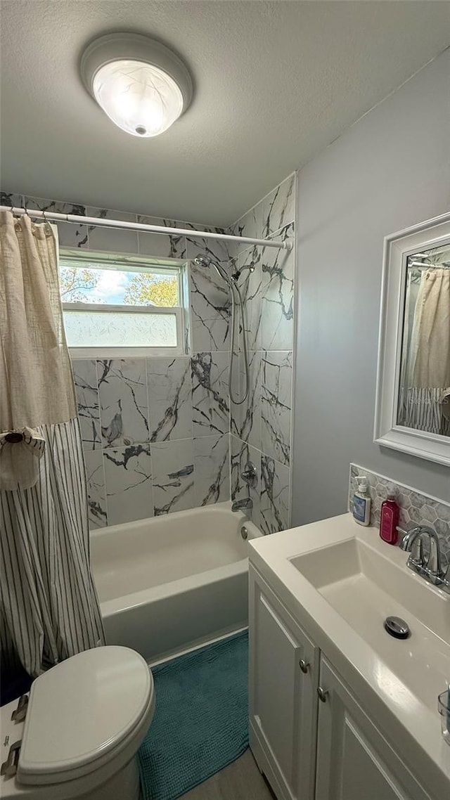 full bathroom with shower / tub combo with curtain, vanity, toilet, and a textured ceiling