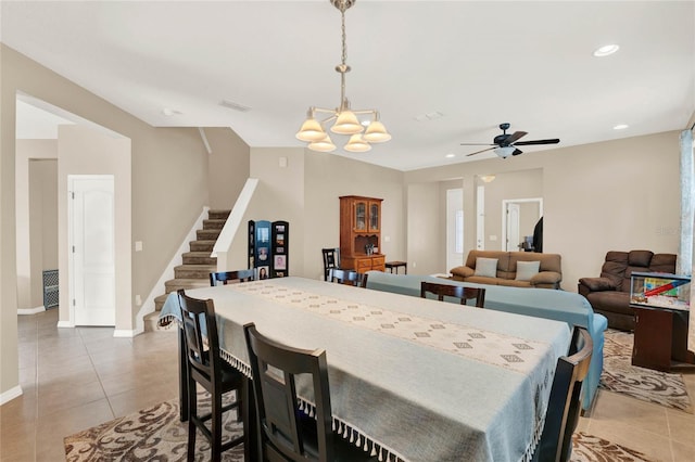 tiled dining room featuring ceiling fan with notable chandelier