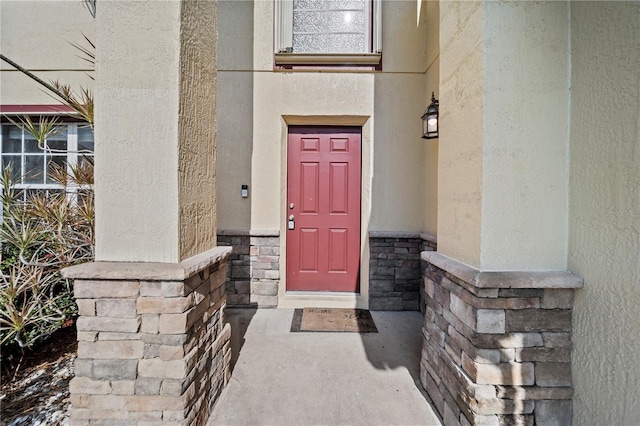 view of exterior entry with stone siding and stucco siding