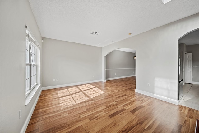 spare room with a textured ceiling and light hardwood / wood-style flooring