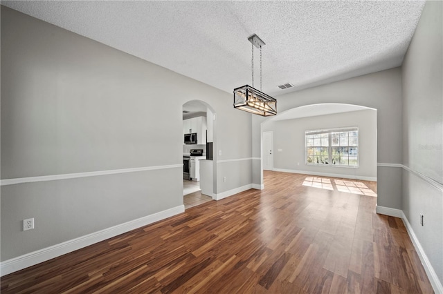 unfurnished dining area with lofted ceiling, wood-type flooring, and a textured ceiling