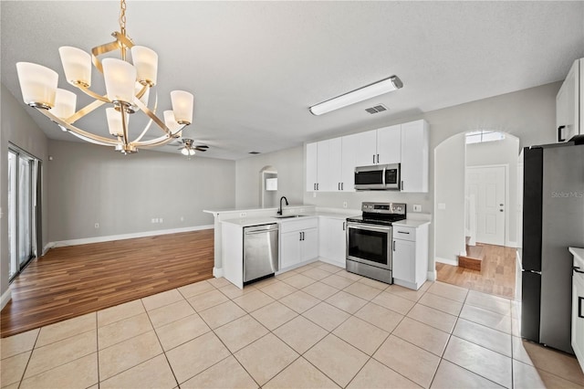 kitchen with appliances with stainless steel finishes, sink, white cabinets, hanging light fixtures, and kitchen peninsula