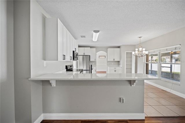 kitchen featuring stainless steel appliances, hanging light fixtures, white cabinets, and kitchen peninsula