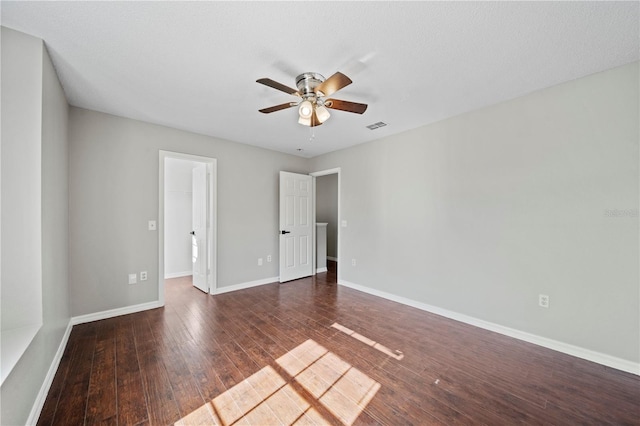 unfurnished bedroom with dark wood-type flooring, a walk in closet, and ceiling fan