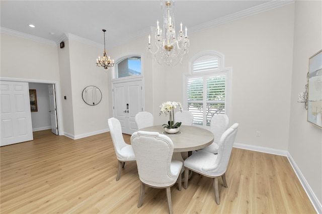 dining room with an inviting chandelier, a towering ceiling, ornamental molding, and light wood-type flooring