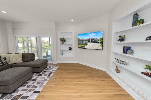 living room featuring built in features and light hardwood / wood-style floors