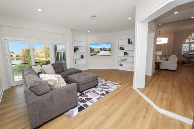 living room with hardwood / wood-style floors, built in shelves, and a chandelier